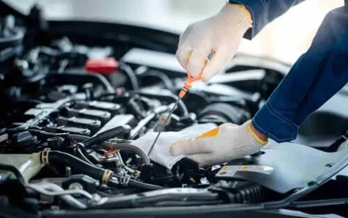 Uomo che esegue la manutenzione dell'auto, controllando l'olio, i freni e altri componenti critici per la sicurezza e l'efficienza dell'auto