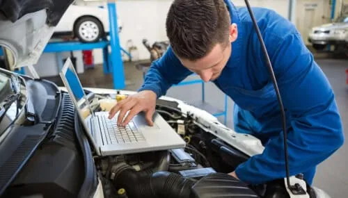 Una persona che esegue la manutenzione di un'auto diesel, con attrezzi e parti di ricambio su un tavolo da lavoro