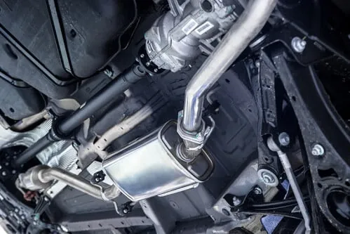 Immagine di un sistema di scarico auto, raffigurante una vista dall'alto di una parte di un motore di un'auto, con una parte del sistema di scarico in primo piano.